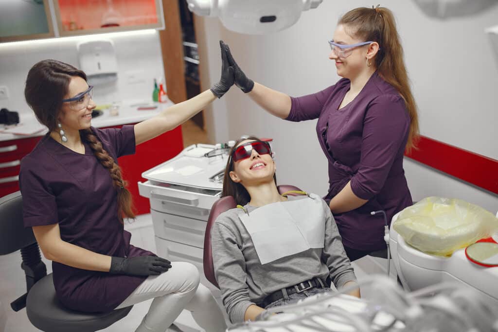Woman smiling in dental chair after cosmetic treatment