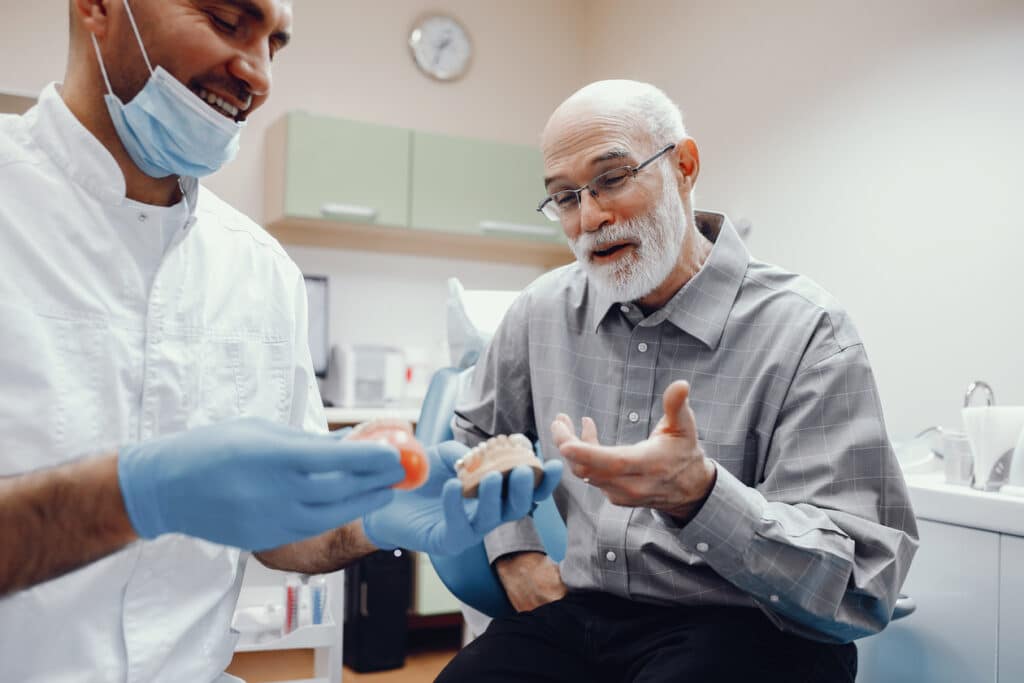 Senior man sitting in dental chair for denture fitting