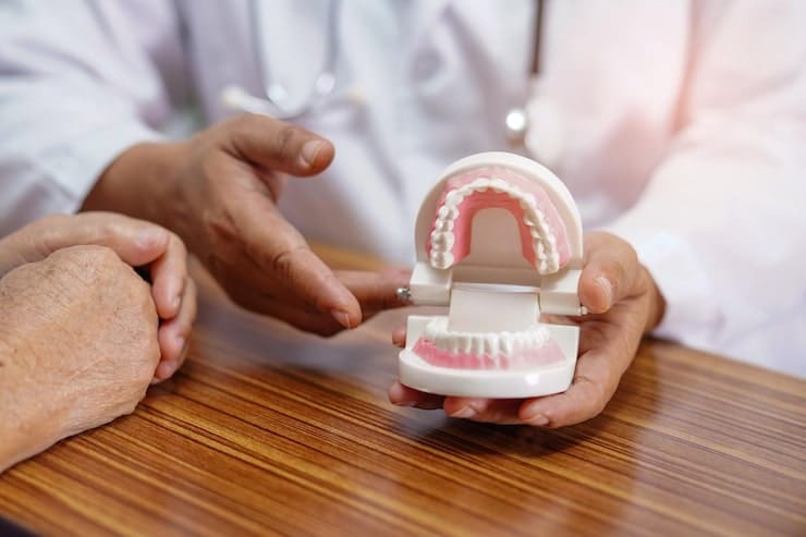 Dentist holding dentures at dental office